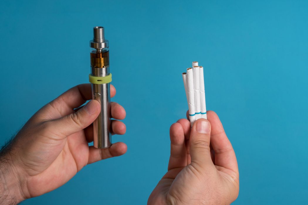 Men holding electronic cigarette on colored background